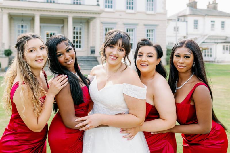 Bridesmaids in red dresses with coordinated champagne makeup looks