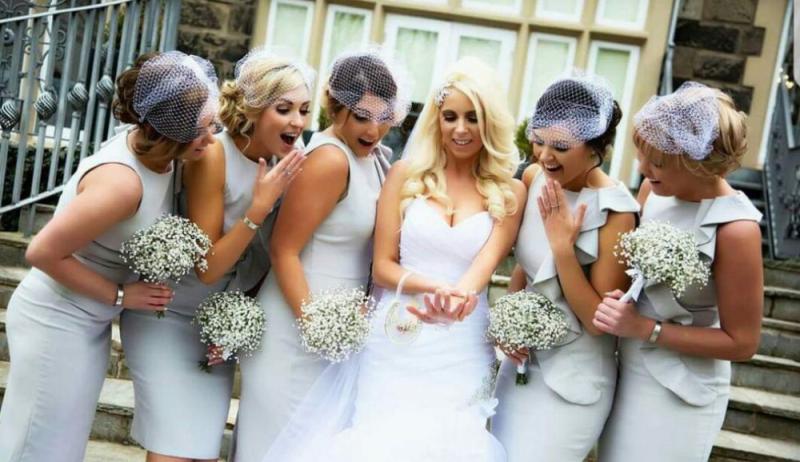 outside wedding with bridesmaids holding flowers alongside bride
