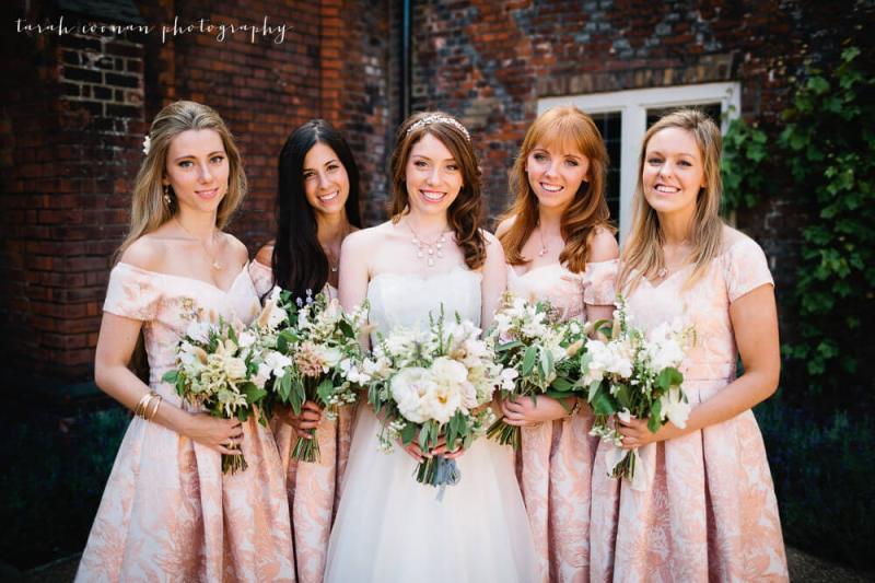 bride and bridesmaids holding flowers smiling