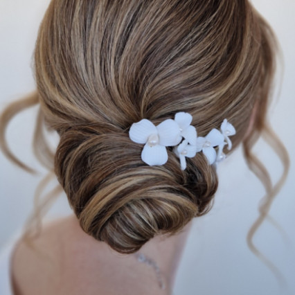 An elegant, perfectly polished bridal bun with swirl detailing. A polymer clay flower accessory offsets the look! - #bridalhair #lowbun #floral #timeless #bridalupdo #bridalbun
